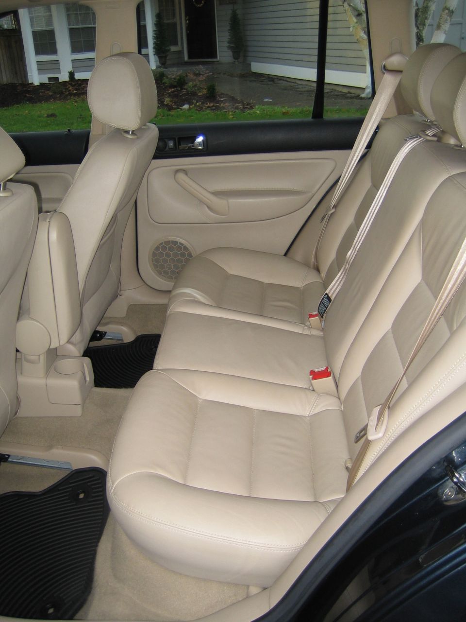 Beige leather rear seats and door panel inside a wagon, viewed through the open rear door