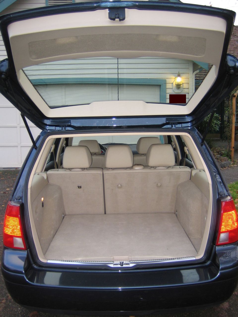Open rear hatch of dark blue VW wagon showing empty tan cargo area