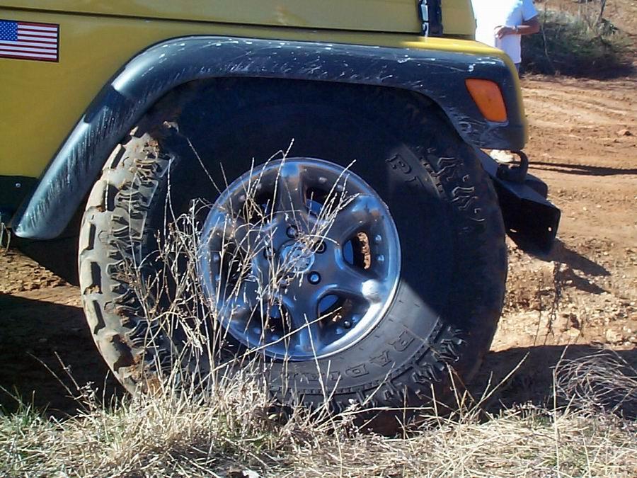 Close-up of yellow Jeep fender, chrome wheel and BFGoodrich tire with US flag decal