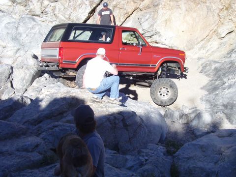 1984 Ford Bronco - This red 1984 Ford Bronco is shown off-roading on a challenging rocky trail.