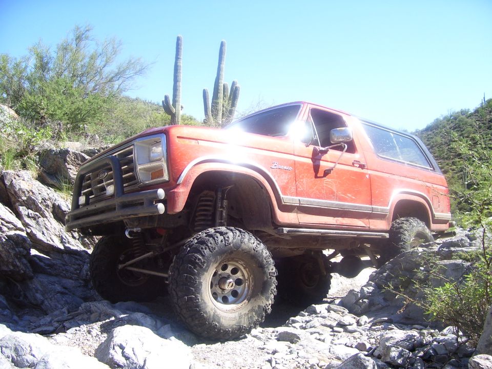 Red SUV climbing rocky terrain with saguaro cacti in background