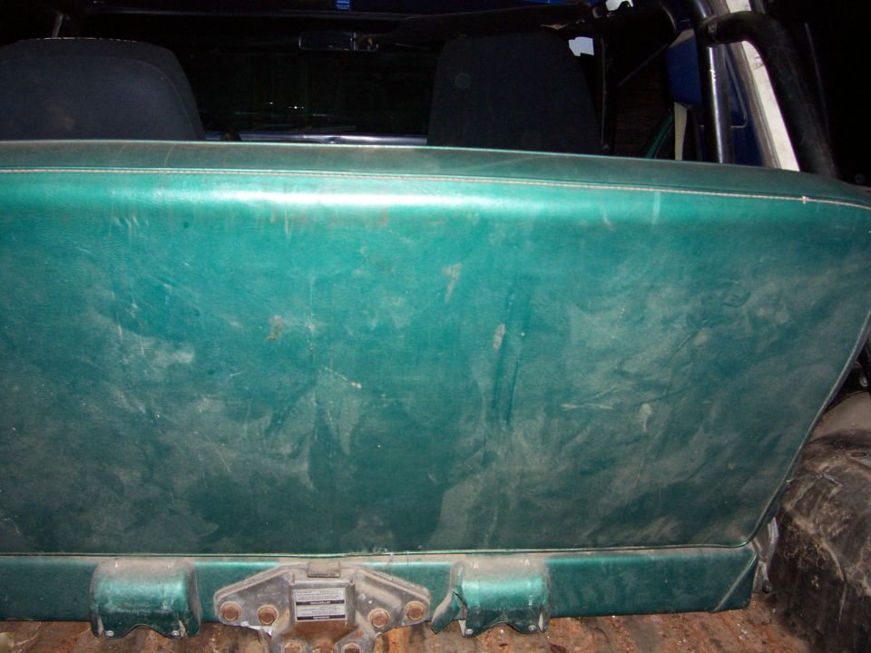 Green interior panel with visible stitching, behind it are dark seats and a roll bar