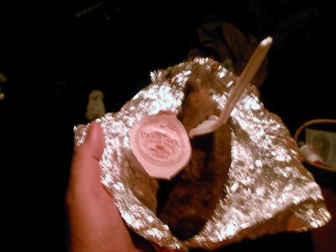 1986 Ford Bronco - A hand holds a foil-wrapped baked potato with a side of sour cream, ready to be eaten.