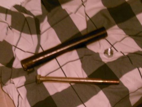 1986 Ford Bronco - A metal pipe and a large bolt are laid out on a checkered blanket.