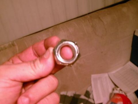 1986 Ford Bronco - A hand holds a single metal nut, obscuring the background.