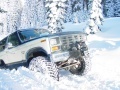 1986 Ford Bronco - A white SUV navigates a snowy landscape, its tires deeply embedded in the snow.
