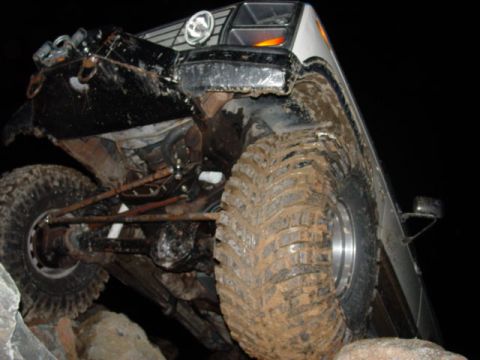 1986 Ford Bronco - This heavily modified off-road vehicle is navigating a rocky terrain at night.