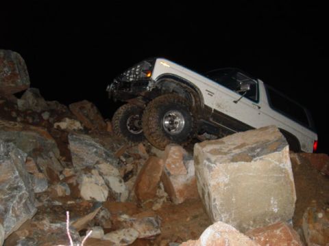 1986 Ford Bronco - This white SUV is navigating a rocky terrain in the dark.
