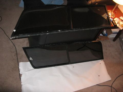 1991 Ford Bronco - Two car door windows are laid out on a carpeted surface, possibly for replacement or storage.