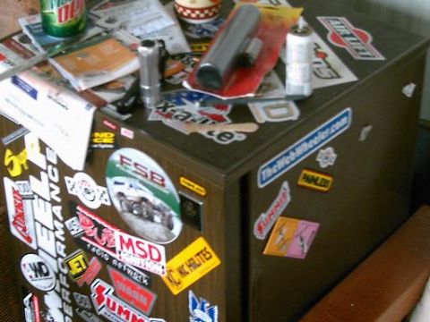 1986 Ford Bronco - A cabinet is heavily adorned with various stickers, obscuring its original appearance.