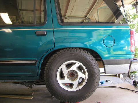 1984 Ford Bronco - The rear side of a teal Ford Explorer is shown, with a focus on the wheel and body panel.