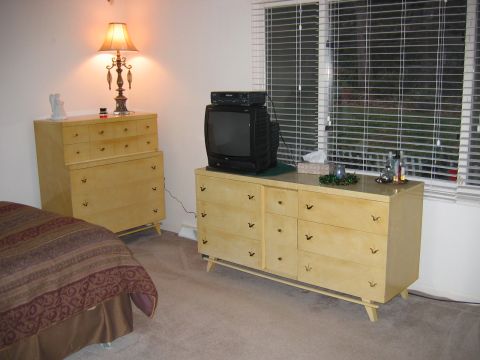 1985 Ford LTD Crown Victoria - A bedroom features a tall dresser and a long dresser with a television and a lamp.