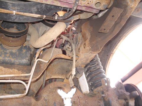 1995 Ford Bronco - A close-up view of the undercarriage reveals suspension parts and engine components, with significant rust present.
