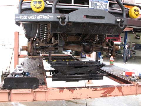 1995 Ford Bronco - Close-up view of a vehicle's front axle and suspension components being serviced on a lift.