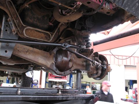 1995 Ford Bronco - Undercarriage view of a vehicle's front axle and steering components, showing signs of rust and wear.