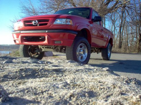 2001 Mazda B3000 - This red 2001 Mazda B3000 pickup truck is shown from a low angle, highlighting its lifted suspension and front grille.