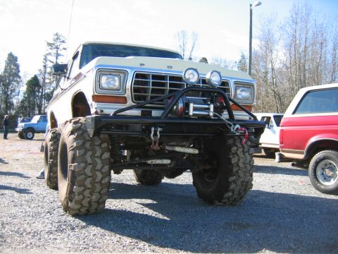 1992 Ford Mustang - This heavily modified 1979 Ford truck features a winch and oversized off-road tires, with other vehicles visible in the background.