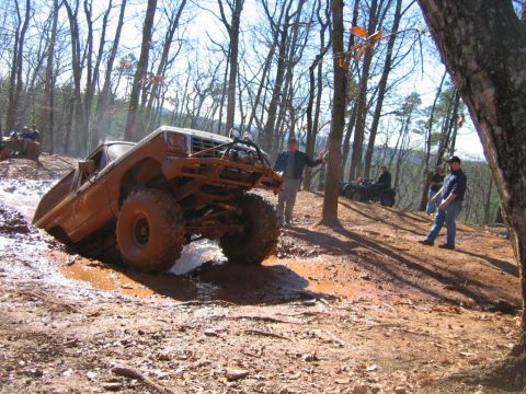 1992 Ford Mustang - Off-road pickup truck struggling through a muddy terrain with spectators nearby.