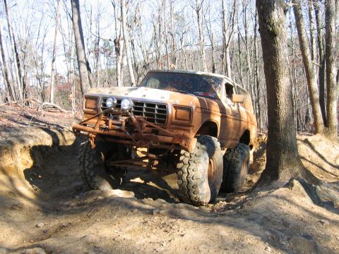 1992 Ford Mustang - A heavily modified 1978 Ford Bronco tackles an off-road trail in a wooded area.