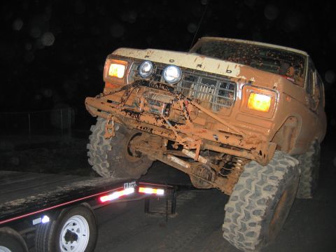 1992 Ford Mustang - Mud-covered 1980s Ford truck with winch and large tires is loaded onto a trailer at night.