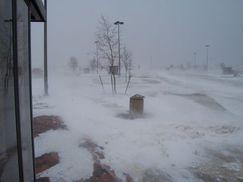 2003 Ford Ranger - A parking lot is covered in blowing snow during a blizzard, with a distant red car barely visible.