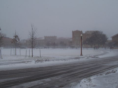 2003 Ford Ranger - A winter scene shows a snow-covered road with tire tracks leading towards buildings obscured by snow and haze.