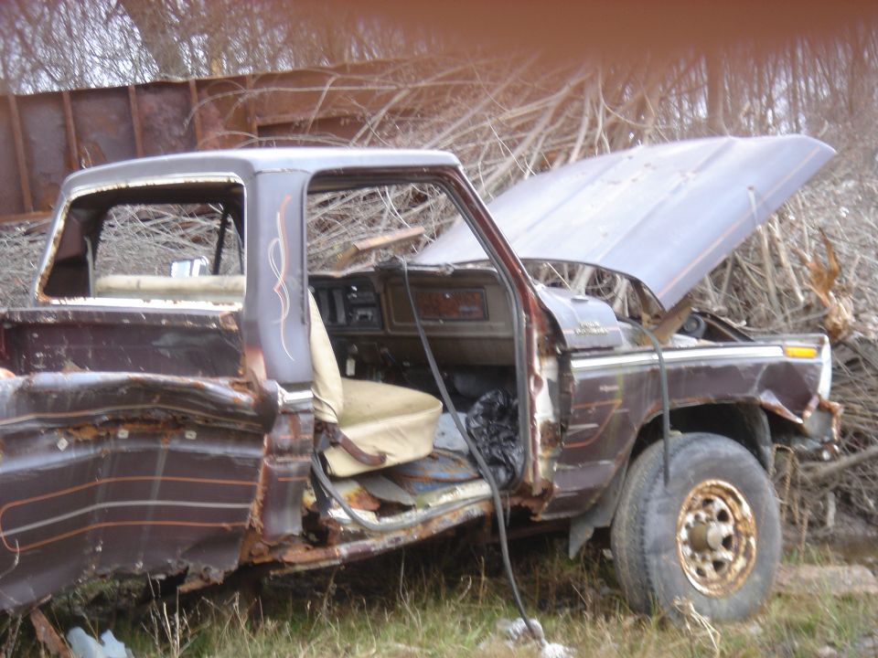 Brown Ford F-Series truck with open hood and doors, showing rust and damage