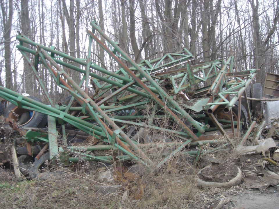 Pile of green metal scrap and tires in a wooded area