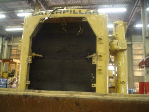 1966 International School Bus - The front grille of a large yellow Caterpillar machine is shown, with exposed wiring and a dark radiator behind it.