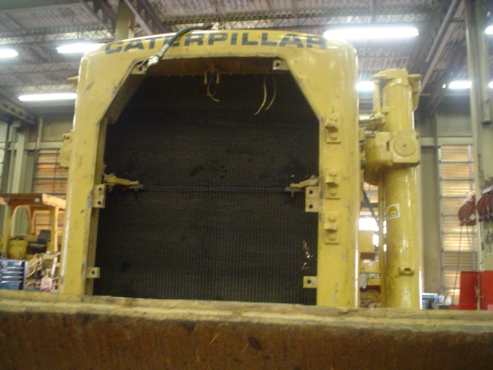 Front view of a yellow Caterpillar machine's radiator grille, with the brand name visible at the top