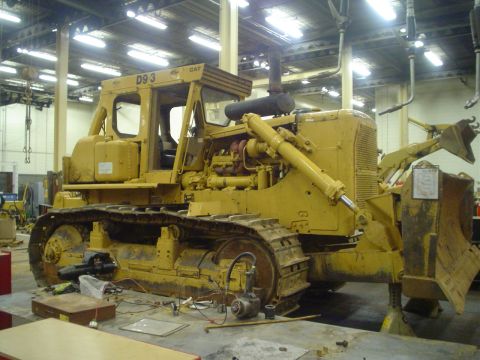 1966 International School Bus - A yellow Caterpillar D9 3 bulldozer sits in a workshop, appearing to be undergoing maintenance or repair.