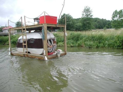 1989 Ford Bronco - Camper trailer converted into a houseboat floats down a canal.