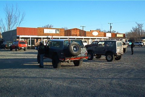 1986 Ford Bronco - Several SUVs are parked in a lot outside a building with a cafe sign. One SUV is viewed from the rear, showing its spare tire.