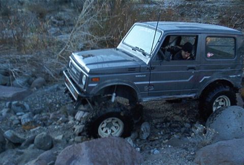 1986 Ford Bronco - This Suzuki Samurai is shown off-roading on a rocky, uneven surface.