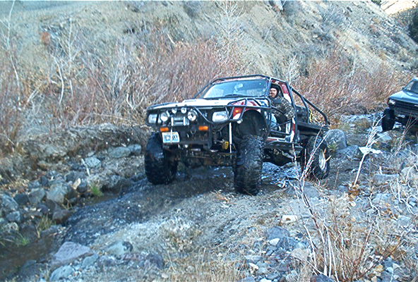 Off-road vehicle with roll cage and large tires on rocky terrain