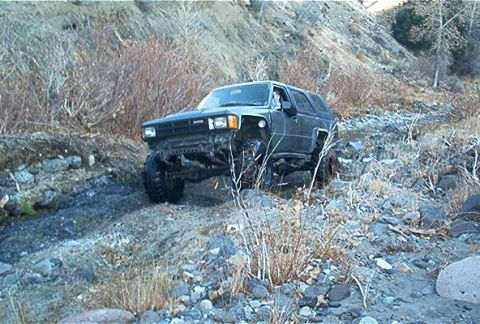 1986 Ford Bronco - This modified Toyota 4Runner is navigating a challenging off-road terrain with large tires and lifted suspension.