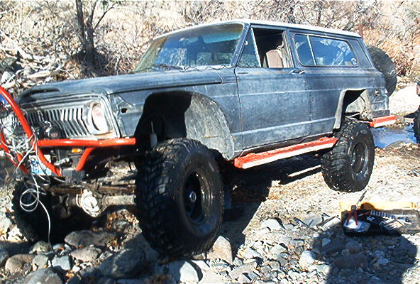 Modified Jeep Wagoneer with large tires and off-road bumper on rocky terrain