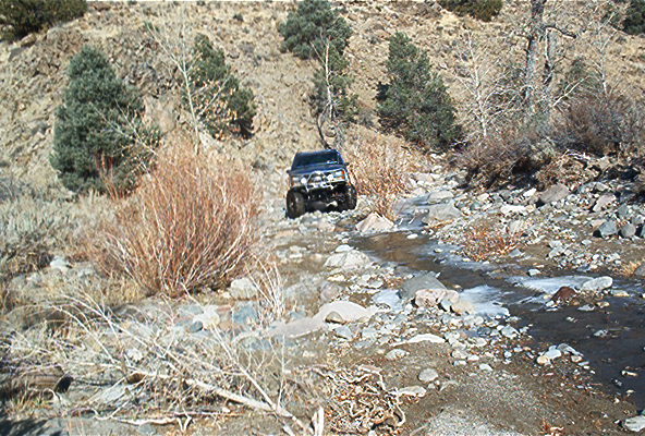 Dark blue SUV navigating a rocky stream bed