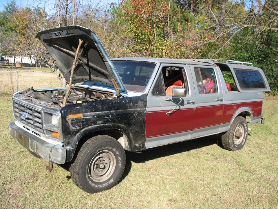 Four-door bullnose Ford 4x4 conversion wagon on grass with hood propped open by a branch