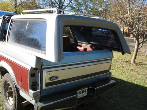 1986 Ford C-350 (Centurion Conversions) - Rear view of a Ford Bronco with its removable top ajar, showing the interior and a license plate.