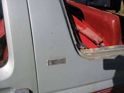 1986 Ford C-350 (Centurion Conversions) - A close-up view of the 'Centurion' badge on the side of a vehicle, with a glimpse of its red interior.