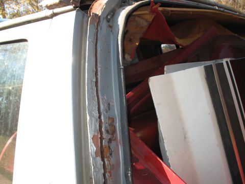 1986 Ford C-350 (Centurion Conversions) - Close-up of a vehicle's door frame, showing signs of wear and rust, with interior components piled inside.