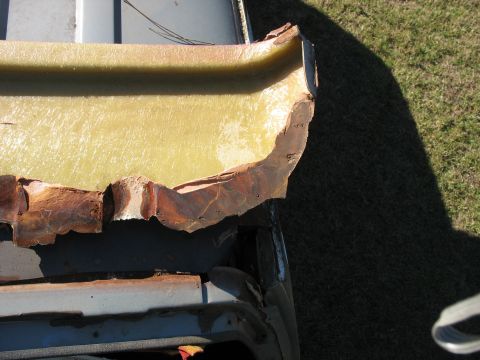 1986 Ford C-350 (Centurion Conversions) - Close-up of damaged fiberglass trim and rusted metal on a vehicle, likely showing wear and tear.