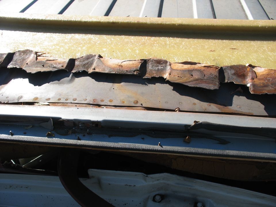 Rotted split wood bed plank and rusted cross sill on a pickup with blue bed sides