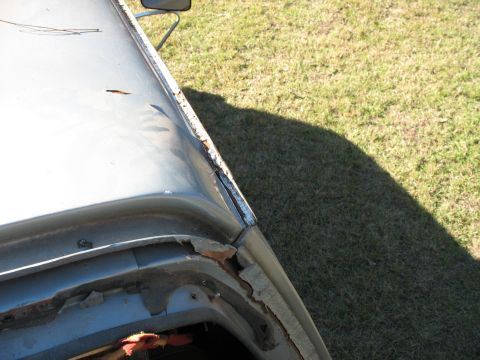 1986 Ford C-350 (Centurion Conversions) - The roof edge of a vehicle shows signs of wear and tear, with exposed sealant and rust.