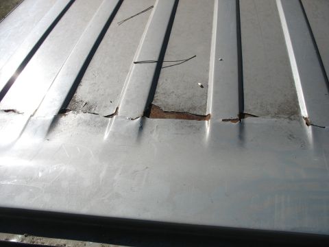 1986 Ford C-350 (Centurion Conversions) - Close-up of a damaged corrugated metal roof showing signs of rust and wear.