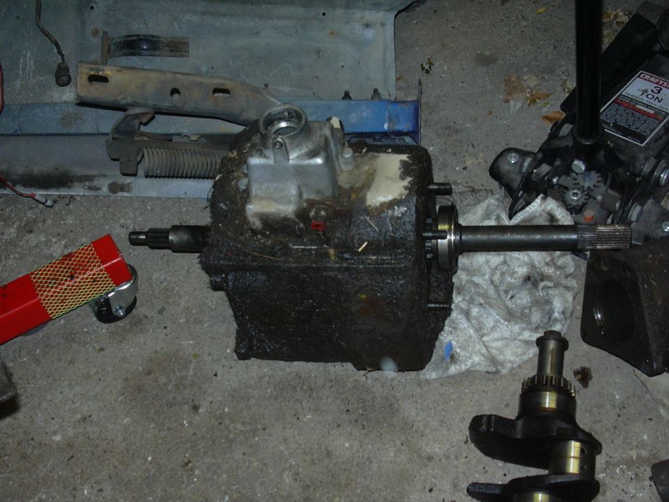 Transmission case with driveshaft attached, and a separate crankshaft on a garage floor
