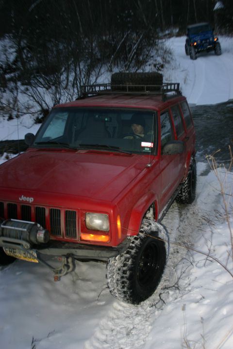 2003 Jeep TJ - Two Jeeps navigating a snowy trail with a stream beside them.
