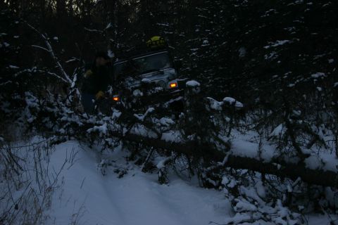 2003 Jeep TJ - A silver Jeep Wrangler navigates a snowy, wooded area with a person standing nearby.