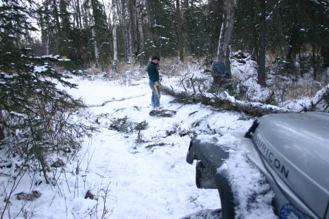 2003 Jeep TJ - A Jeep Wrangler Rubicon is parked in a snowy forest while a person works to clear fallen branches from a path.